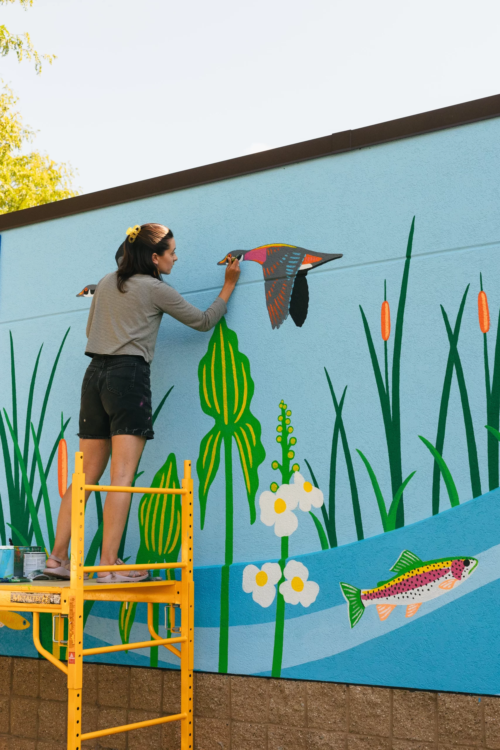 Artist Natalie Hinahara painting her mural at Bauman Community Pool in Middleton Wisconsin 