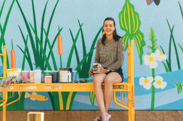 Artist Natalie Hinahara in front of the mural she painted at Bauman Community Pool in Middleton Wisconsin