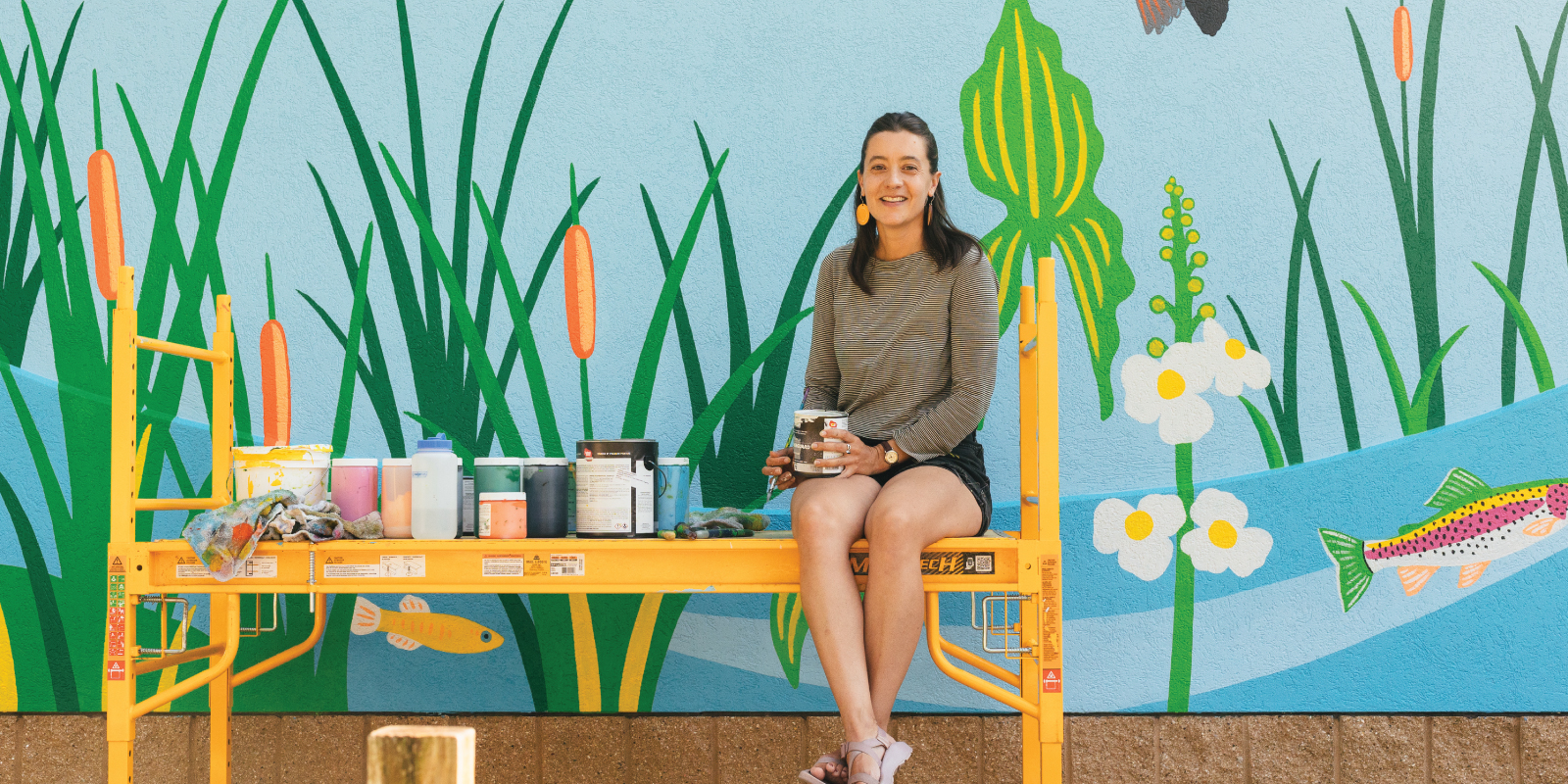 Artist Natalie Hinahara in front of the mural she painted at Bauman Community Pool in Middleton Wisconsin